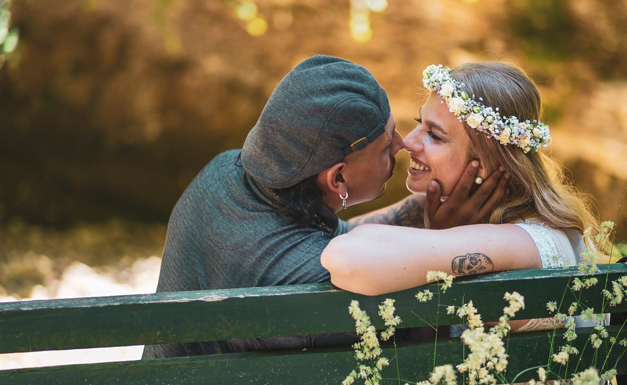 Brautpaar küsst sich auf einer Parkbank – Hochzeit von Tina & Will