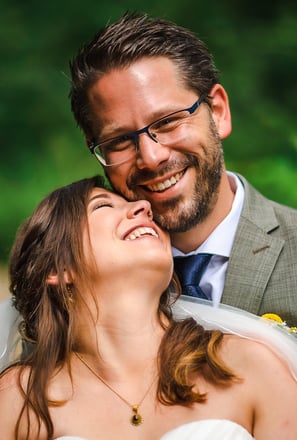 Braut lacht mit geschlossenen Augen in den Armen des Bräutigams – Hochzeit von Misch & Simu