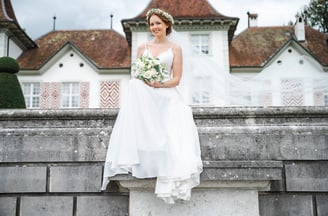 Braut sitzt vor der Fassade von Schloss Waldegg – Hochzeit von Romana & Remo