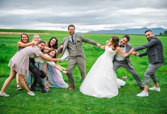 Brautpaar und Freunde beim lustigen Gruppenfoto auf der Wiese – Hochzeit von Misch & Simu