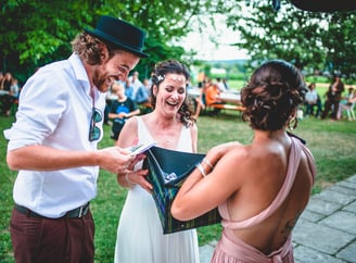 Brautpaar packt im Garten ein Geschenk aus – Hochzeit von Rege & Sven