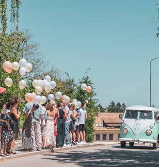 Grüner VW-Bus als Hochzeitsauto, Gäste mit Ballonen am Strassenrand – Hochzeit von Tina & Will