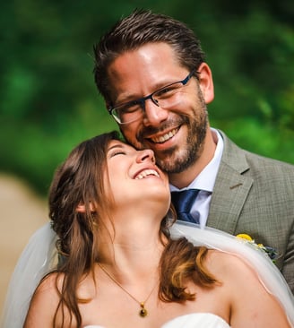 Braut lacht mit geschlossenen Augen in den Armen des Bräutigams – Hochzeit von Misch & Simu