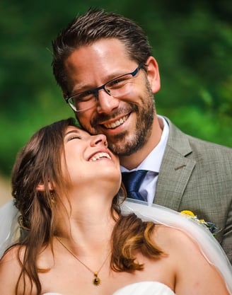Braut lacht mit geschlossenen Augen in den Armen des Bräutigams – Hochzeit von Misch & Simu
