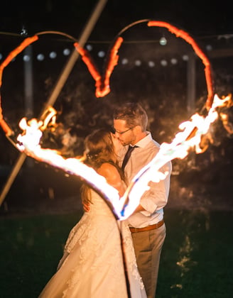 Brautpaar küsst sich vor einem brennenden Feuerherz – Hochzeit von Misch & Simu