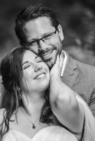 Braut schmiegt sich lachend an den Bräutigam, Schwarz-Weiss – Hochzeit von Misch & Simu