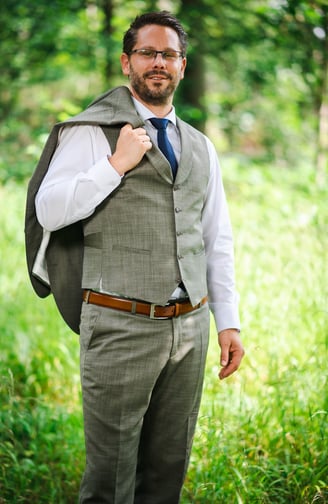 Bräutigam mit Jacke über der Schulter im Wald – Hochzeit von Misch & Simu