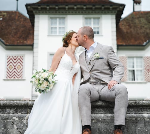 Brautpaar küsst sich vor Schloss Waldegg – Hochzeit von Romana & Remo