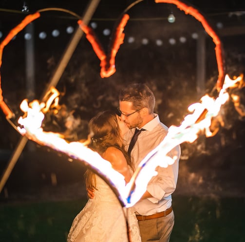 Brautpaar küsst sich vor einem brennenden Feuerherz – Hochzeit von Misch & Simu