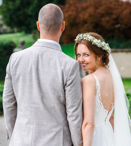Braut blickt über die Schulter, Hand in Hand mit dem Bräutigam – Hochzeit von Romana & Remo