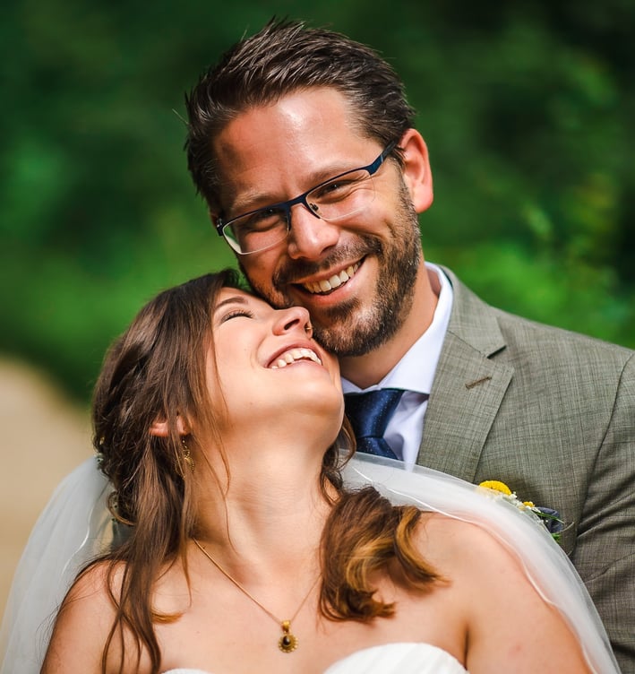 Braut lacht mit geschlossenen Augen in den Armen des Bräutigams – Hochzeit von Misch & Simu