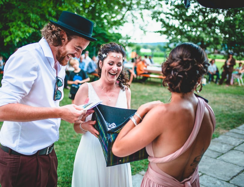 Brautpaar packt im Garten ein Geschenk aus – Hochzeit von Rege & Sven