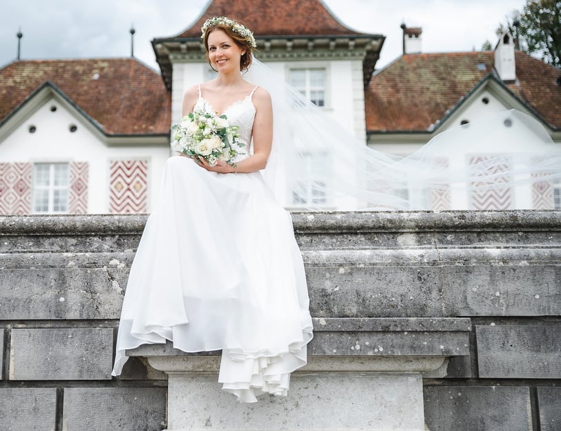 Braut sitzt vor der Fassade von Schloss Waldegg – Hochzeit von Romana & Remo